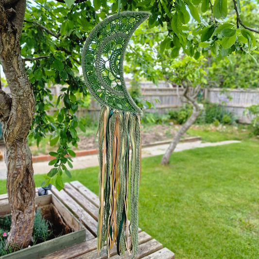 Handmade crochet Moon dreamcatcher with green and gold ribbons and fringe, perfect for boho wall décor and nursery spaces.