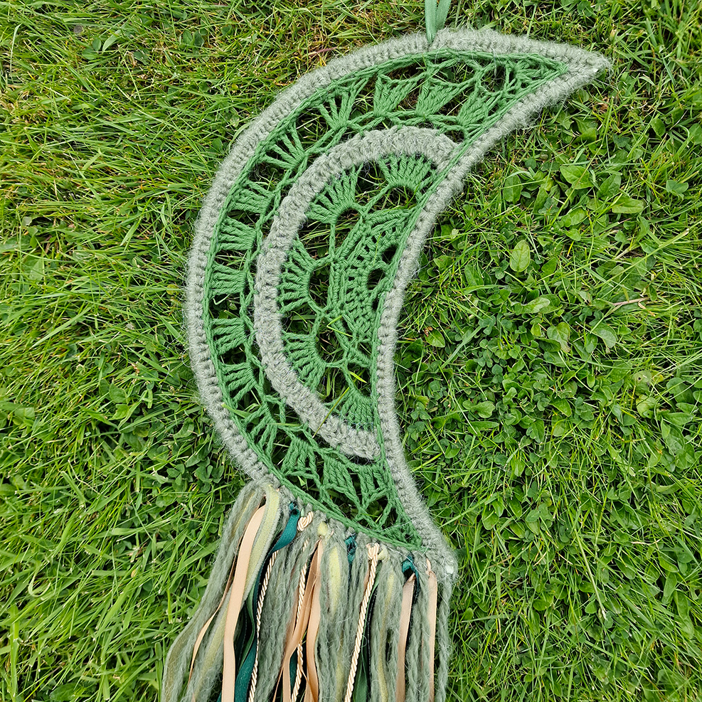 Handmade crochet Moon dreamcatcher with green and gold ribbons and fringe, perfect for boho wall décor and nursery spaces.
