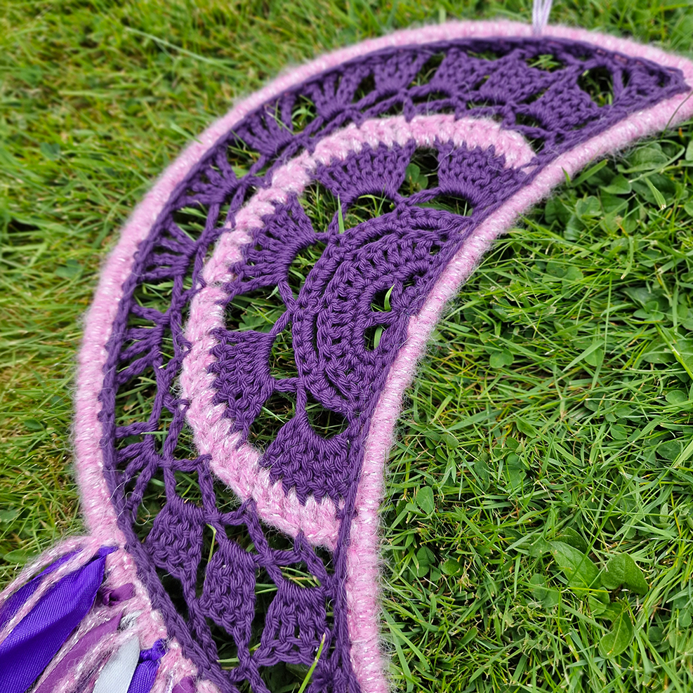 Handmade crochet Moon dreamcatcher with purple and pink ribbons and fringe, perfect for boho wall décor and nursery spaces.