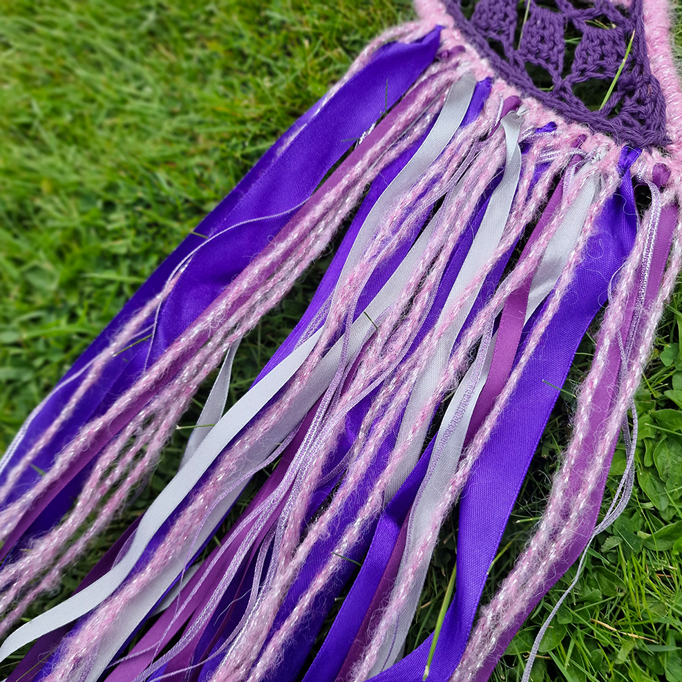 Handmade crochet Moon dreamcatcher with purple and pink ribbons and fringe, perfect for boho wall décor and nursery spaces.