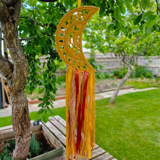 Handmade crochet Moon dreamcatcher with yellow and burnt orange and fringe, perfect for boho wall décor and nursery spaces.