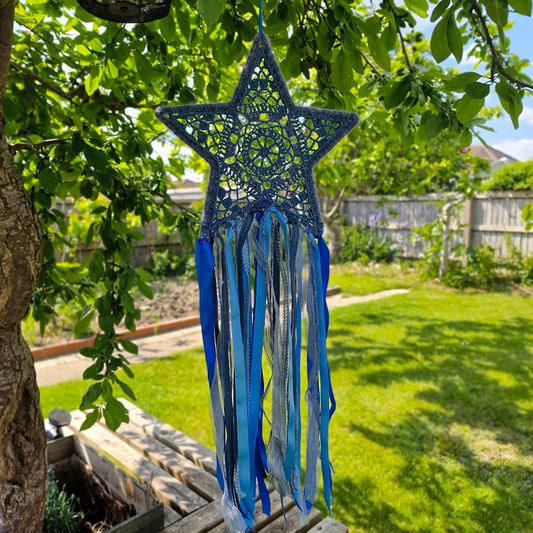 Handmade crochet star dreamcatcher with Blue and silver ribbons and fringe, perfect for boho wall décor and nursery spaces.