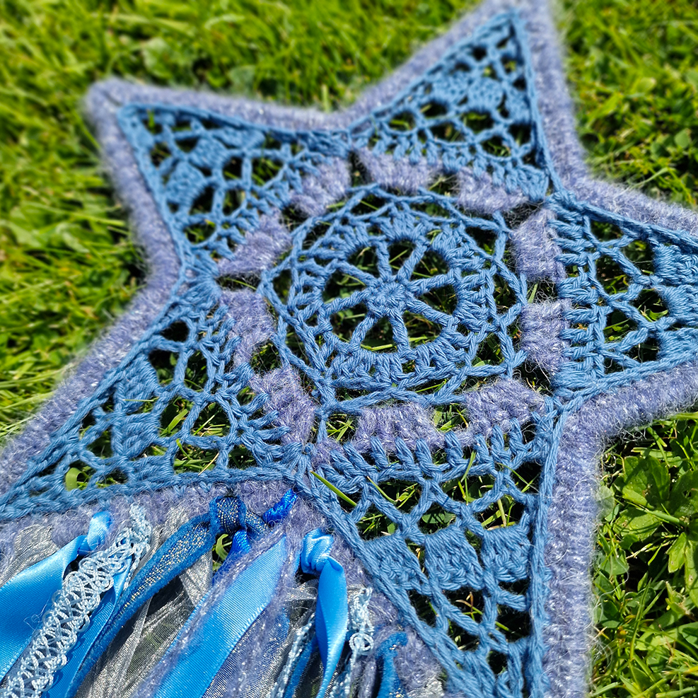 Handmade crochet star dreamcatcher with Blue and silver ribbons and fringe, perfect for boho wall décor and nursery spaces.