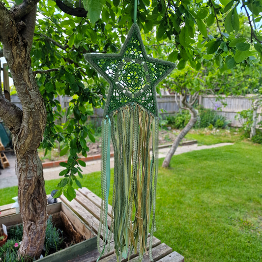 Handmade crochet star dreamcatcher with green and gold and fringe, perfect for boho wall décor and nursery spaces.