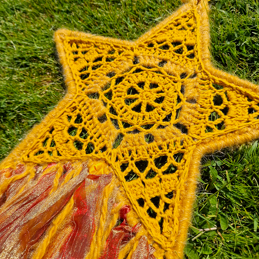 Handmade crochet star dreamcatcher with yellow, orange and brown ribbons and fringe, perfect for boho wall décor and nursery spaces.