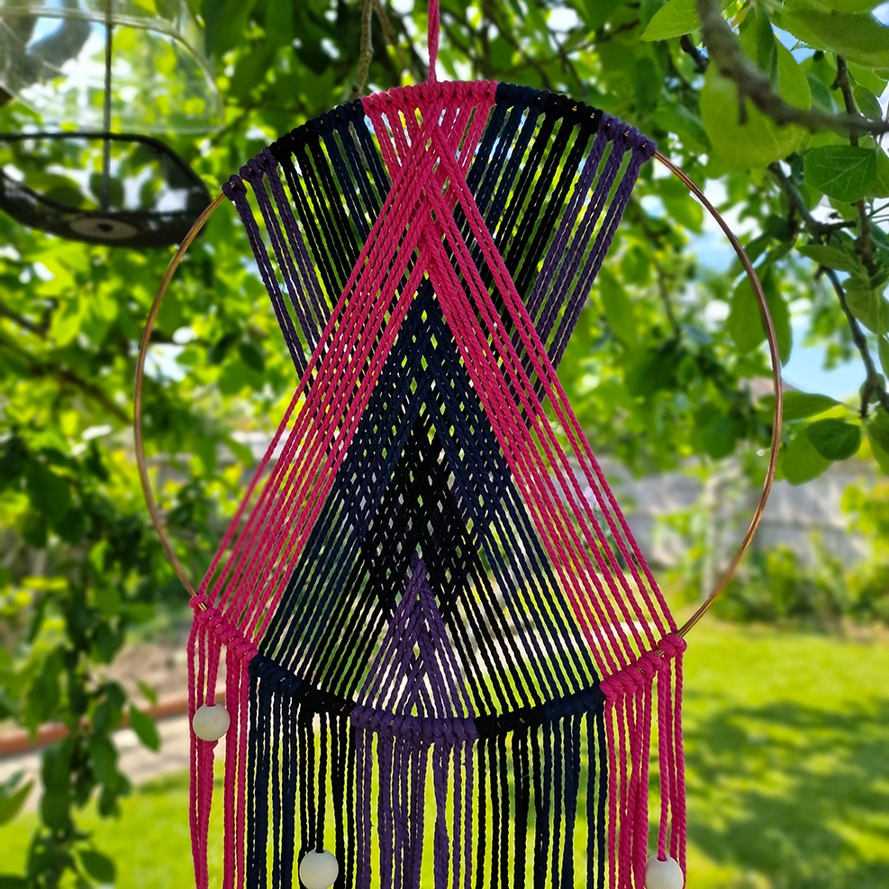 Handcrafted geometric macramé wall hanging in purple, pink, blue and black colours with beads for boho décor