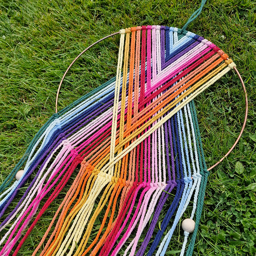 Handcrafted geometric macramé wall hanging in rainbow colours (Red, Yellow, Orange and Green) with beads for boho décor