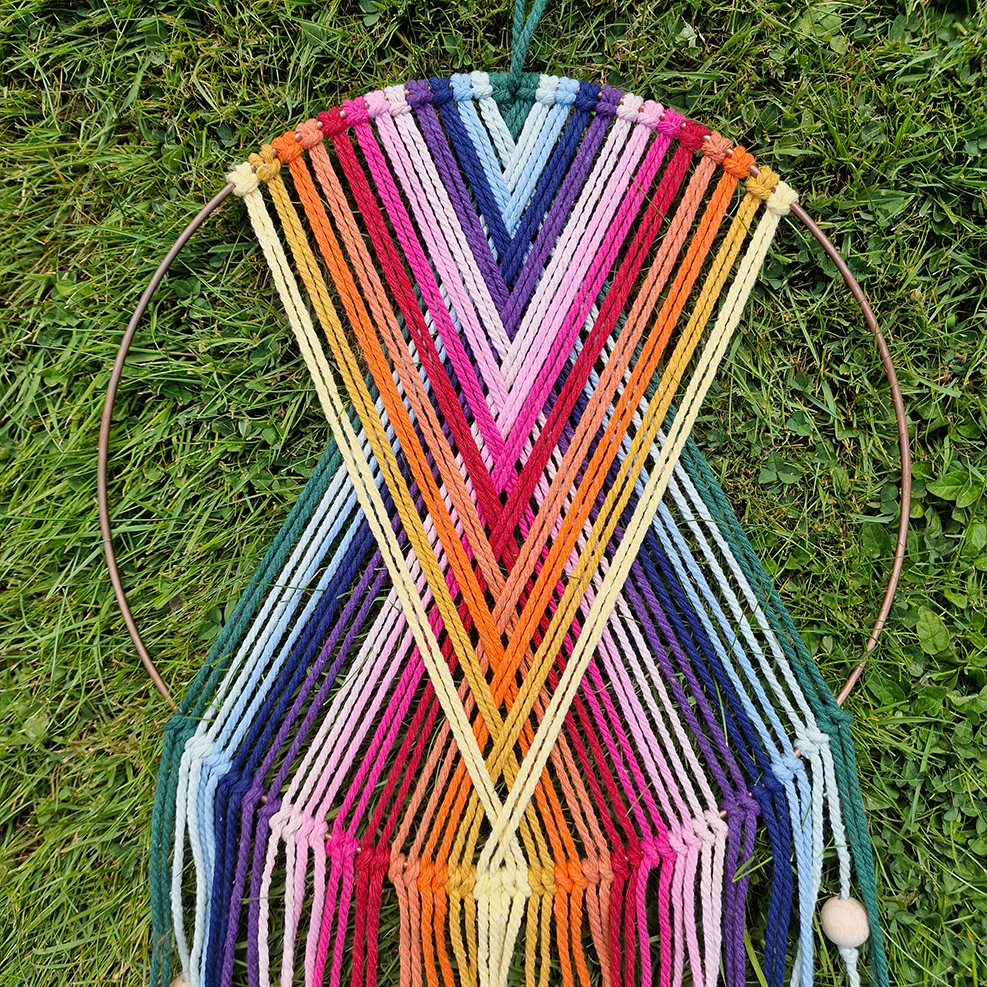 Handcrafted geometric macramé wall hanging in rainbow colours (Red, Yellow, Orange and Green) with beads for boho décor