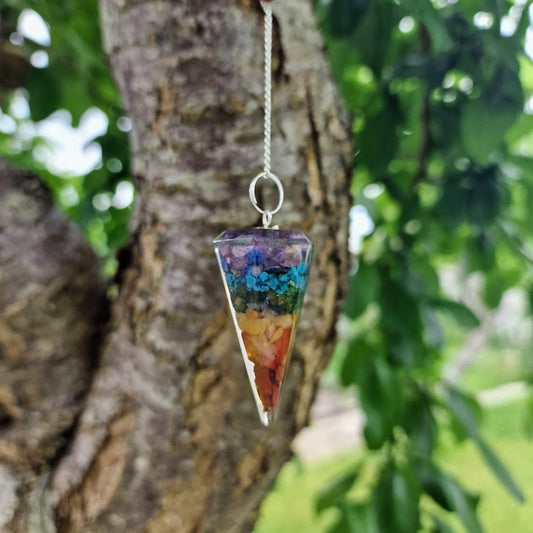 Colourful chakra resin pendulum with embedded stones and a silver chain featuring seven chakra crystal beads for energy healing and spiritual alignment.