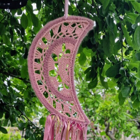 Handmade crochet Moon dreamcatcher with pink ribbons and fringe, perfect for boho wall decor and nursery spaces.