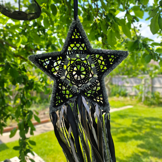 Handmade crochet star dreamcatcher with black, grey and silver/gold ribbons and fringe, perfect for boho wall décor and nursery spaces.