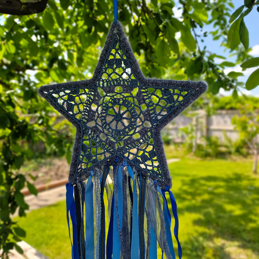 Handmade crochet star dreamcatcher with Blue and silver ribbons and fringe, perfect for boho wall décor and nursery spaces.