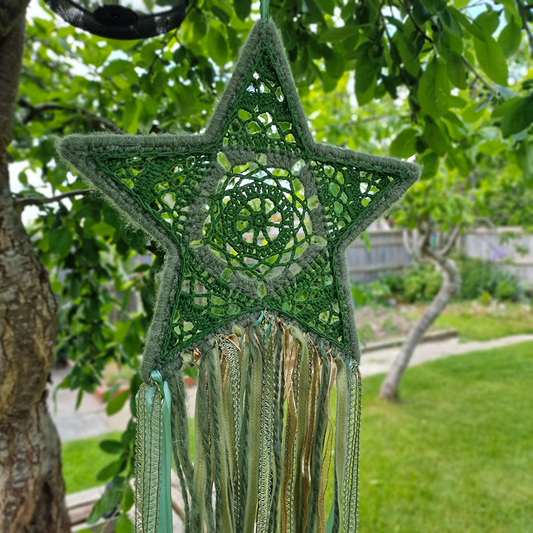 Handmade crochet star dreamcatcher with green and gold and fringe, perfect for boho wall décor and nursery spaces.