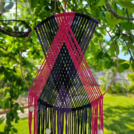 Handcrafted geometric macramé wall hanging in purple, pink, blue and black colours with beads for boho décor
